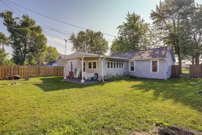 a white house with a fence in a yard at Downtown Russells Point Cottage Near Indian Lake! in Russells Point