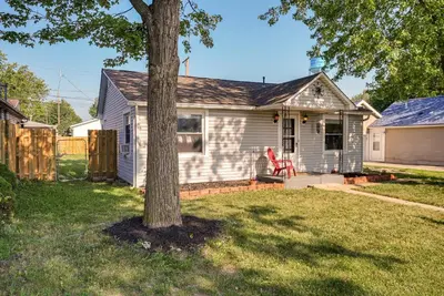 a white house with a tree in the yard at Downtown Russells Point Cottage Near Indian Lake! in Russells Point