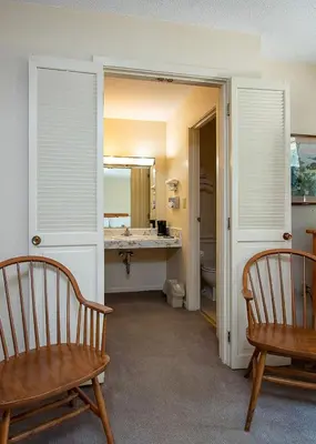 a bathroom with two wooden chairs and a sink at Country Squire inn and suites in Coshocton