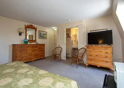 a bedroom with a bed and a dresser with a flat screen tv at Country Squire inn and suites in Coshocton