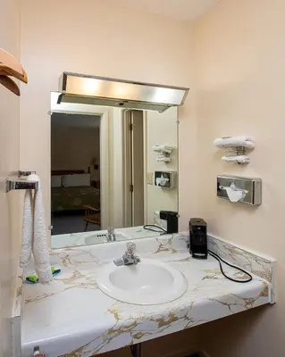 a bathroom with a sink and a mirror at Country Squire inn and suites in Coshocton