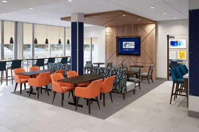 a restaurant with tables and chairs and a tv at Holiday Inn Express & Suites Lima by IHG in Lima
