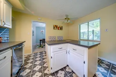 a kitchen with white cabinets and a ceiling fan at Richmond Heights Retreat with Patio and Fire Pit! in Richmond Heights