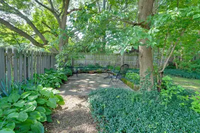 a bench sitting under a tree in a garden at Welcoming Willoughby Home 1 Mi to Historic Dtwn in Willoughby
