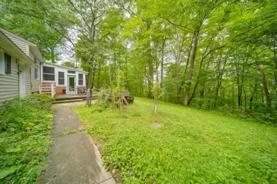 a backyard of a house with a lawn and trees at Stylish Willoughby Hills Retreat with Fireplace! in Willoughby Hills