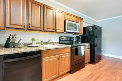 a kitchen with wooden cabinets and a black refrigerator at Toledo Vacation Rental about 5 Mi to Downtown! in Toledo