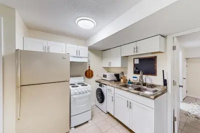 a kitchen with white cabinets and a sink and a refrigerator at River Access! Couples Retreat on Working Homestead in Woodburn