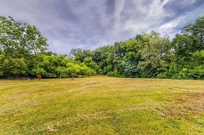a large grass field with trees in the background at River Access! Couples Retreat on Working Homestead in Woodburn