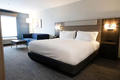 a hotel room with a bed and a blue chair at Holiday Inn Express & Suites Mansfield - Ontario by IHG in Mansfield