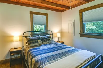 a bedroom with a bed with two lamps and two windows at Creek, Trails and Falls! Rural Red River Gorge Cabin in Campton