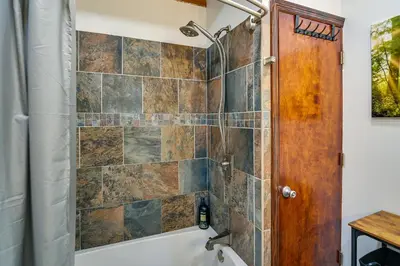 a bathroom with a shower and a tub and a toilet at Creek, Trails and Falls! Rural Red River Gorge Cabin in Campton