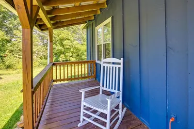 a porch with a white rocking chair on a house at Creek, Trails and Falls! Rural Red River Gorge Cabin in Campton