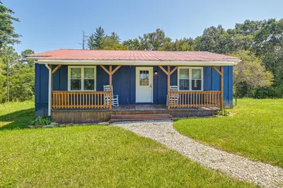 a blue tiny house with a porch in a field at Creek, Trails and Falls! Rural Red River Gorge Cabin in Campton