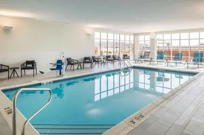 a swimming pool with chairs and tables in a building at SpringHill Suites by Marriott Canfield in Canfield