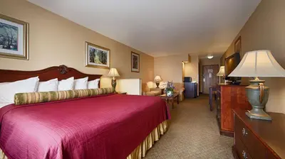 a bedroom with a large bed with a red bedspread at Best Western Penn-Ohio Inn & Suites in Hubbard
