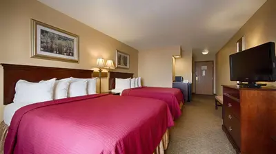 a hotel room with two beds and a flat screen tv at Best Western Penn-Ohio Inn & Suites in Hubbard