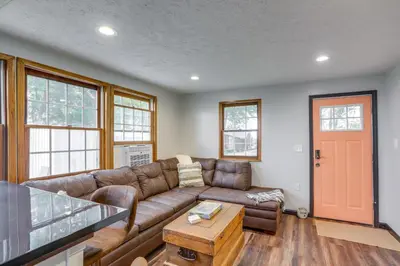 a living room with a brown couch and a table at Vickery Cottage on Sandusky Bay with Fire Pit! in Port Clinton