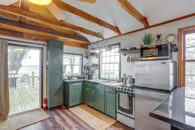 a kitchen with green cabinets and a stove top oven at Vickery Cottage on Sandusky Bay with Fire Pit! in Port Clinton