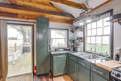 a kitchen with green cabinets and a large window at Vickery Cottage on Sandusky Bay with Fire Pit! in Port Clinton