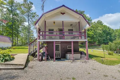 a pink house with a porch and a balcony at Dog-Friendly Home Rental about 5 Mi to Cave Run Lake! in Wellington