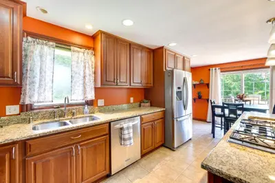 a kitchen with orange walls and wooden cabinets at Bolivar Getaway Near Pro Football Hall of Fame! in Bolivar