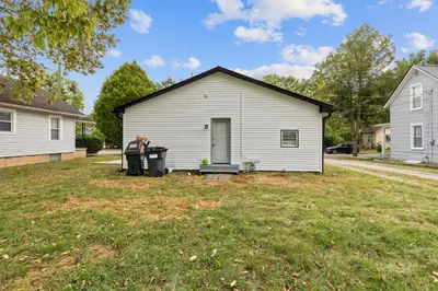 a man standing in front of a white house at Elm Two Bedroom House in Historic Loveland in Loveland