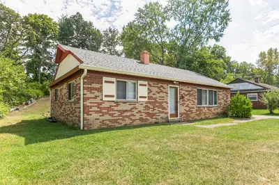 a small brick house with a grass yard at Cozy Retreat in Cincinnati home in Cincinnati