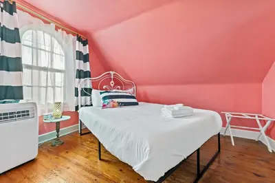a pink bedroom with a bed and a window at Cottage for 12, Close to Ark, Private Parking, 4BR in Williamstown