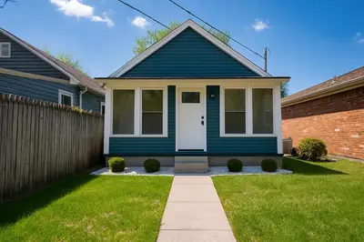 a blue house with a white door in a yard at Buckeye Lake Cottage