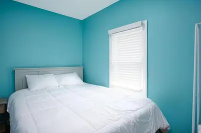 a blue bedroom with a white bed and a window at Buckeye Lake Cottage