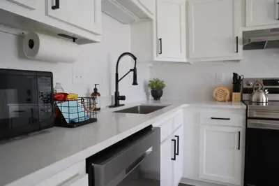 a white kitchen with a sink and a microwave at 5-BR Serene Retreat Near CLE* Dogs welcome! in Berea