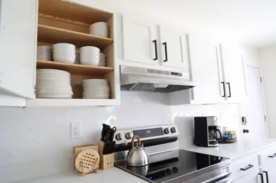 a kitchen with white cabinets and a stove top oven at 5-BR Serene Retreat Near CLE* Dogs welcome! in Berea