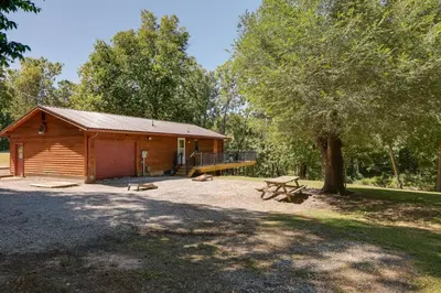 a wooden cabin with a picnic table and a tree at Riverfront Covington Cabin with Deck and Fire Pit! in Piqua