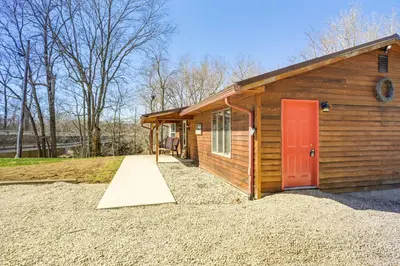 a small wooden cabin with a red door at Riverfront Covington Cabin with Deck and Fire Pit! in Piqua