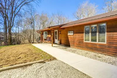 a home with a wooden house with a porch at Riverfront Covington Cabin with Deck and Fire Pit! in Piqua