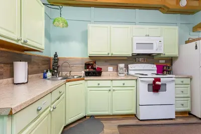 a kitchen with green cabinets and a white refrigerator at Frog Hollow at Hocking Vacations in Logan