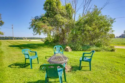 three chairs and a table in the grass at Cozy Greenwich Vacation Rental with Fire Pit in Greenwich