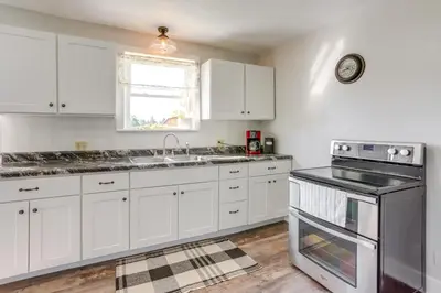 a kitchen with white cabinets and a sink and a stove at Cozy Greenwich Vacation Rental with Fire Pit in Greenwich