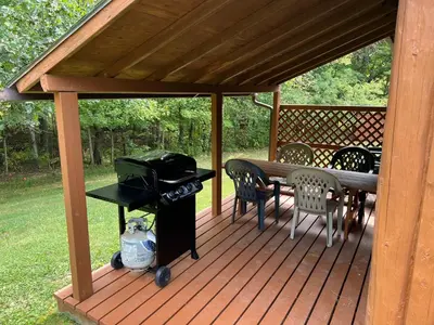 a wooden deck with a grill and a table and chairs at Athens and Albany's Hillside Haven in Albany
