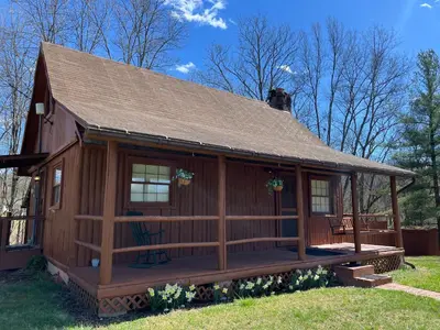 a log cabin with a porch and a dog on the roof at Athens and Albany's Hillside Haven in Albany