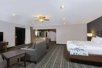 a hotel room with a bed and a living room at Baymont by Wyndham Lancaster in Lancaster