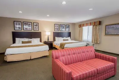 a hotel room with two beds and a couch at Baymont by Wyndham Lancaster in Lancaster