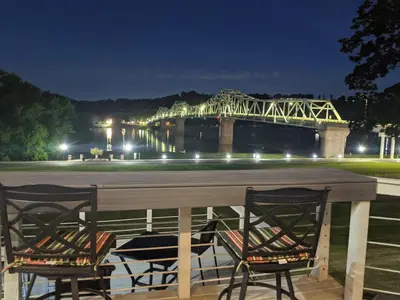 a table with chairs and a bridge at night at Riverboat Inn & Suites in Madison