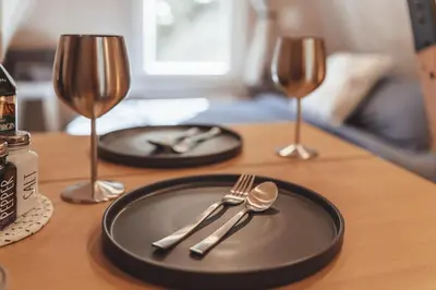 a table with a black plate and silverware and wine glasses at Blue Brambler Glamping A-Frame in Rockbridge