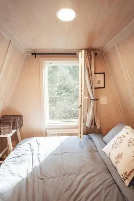 a bed in a small room with a window at Blue Brambler Glamping A-Frame in Rockbridge