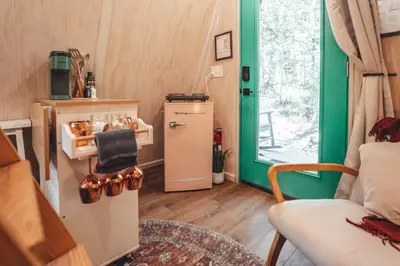 a small refrigerator in a room with a green door at The Green Glamping Getaway in Rockbridge