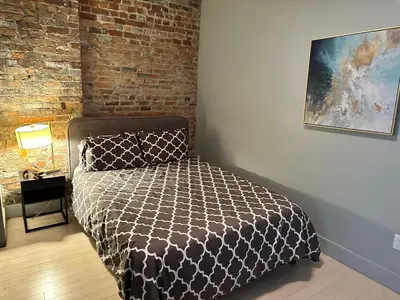 a bedroom with a bed and a brick wall at Cozy Apartment in Historic OTR in Cincinnati