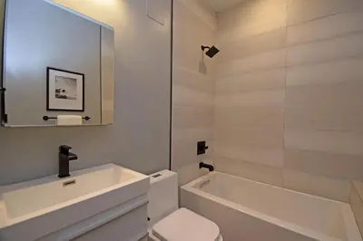 a white bathroom with a tub and a toilet and a sink at Cozy Apartment in Historic OTR in Cincinnati
