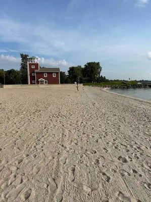 a sandy beach with a red building in the background at Lakeside Oasis/Golf Cart/Beach in Luna Pier