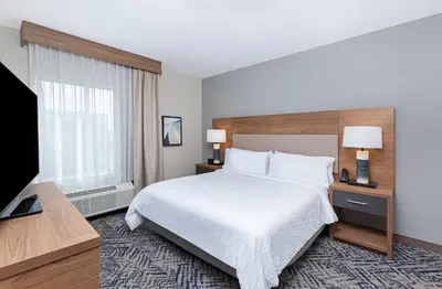 a hotel room with a bed and a flat screen tv at Candlewood Suites Erlanger - South Cincinnati by IHG in Erlanger